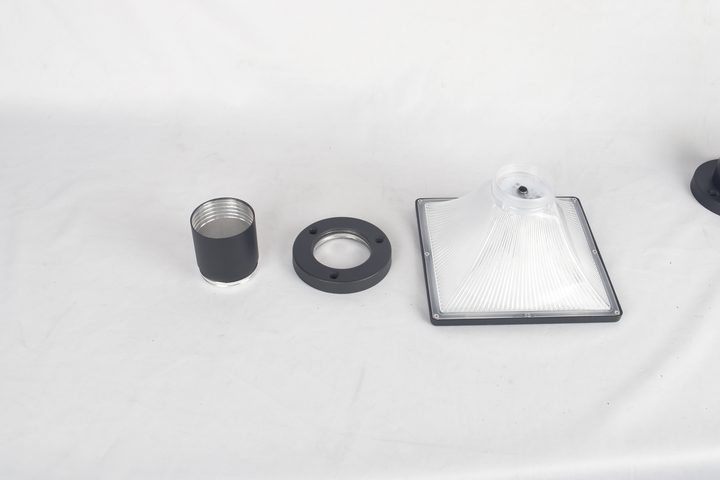 Clear square lamp component beside detached sleeve and round flange