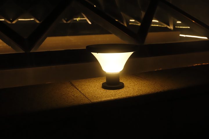 Short round-head tapered-diffuser lamp illuminated on a stone ledge