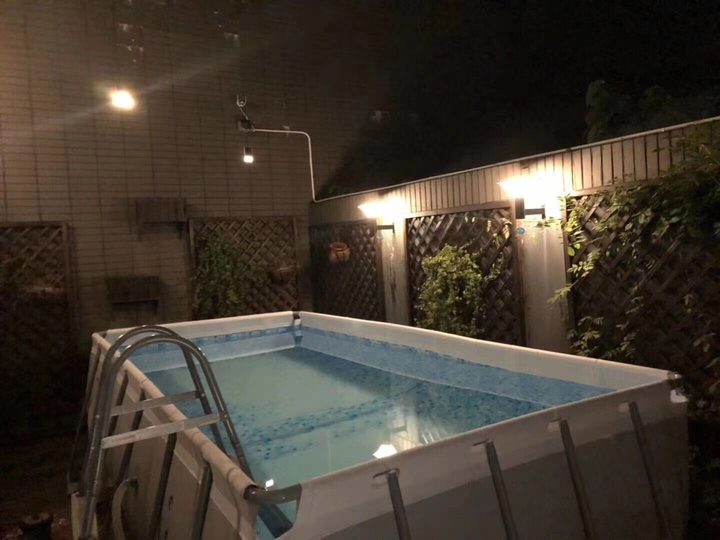 Opaque square lamps pictured along a trellis wall at night.